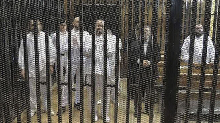 Ousted former Egyptian president Mursi stands with other senior figures of the Muslim Brotherhood in a cage in a courthouse on the first day of his trial, in Cairo